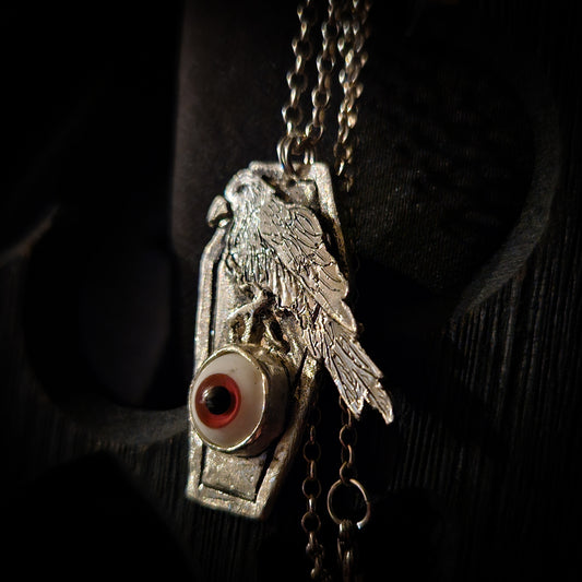 Silver pendant with an eye design on a dark background