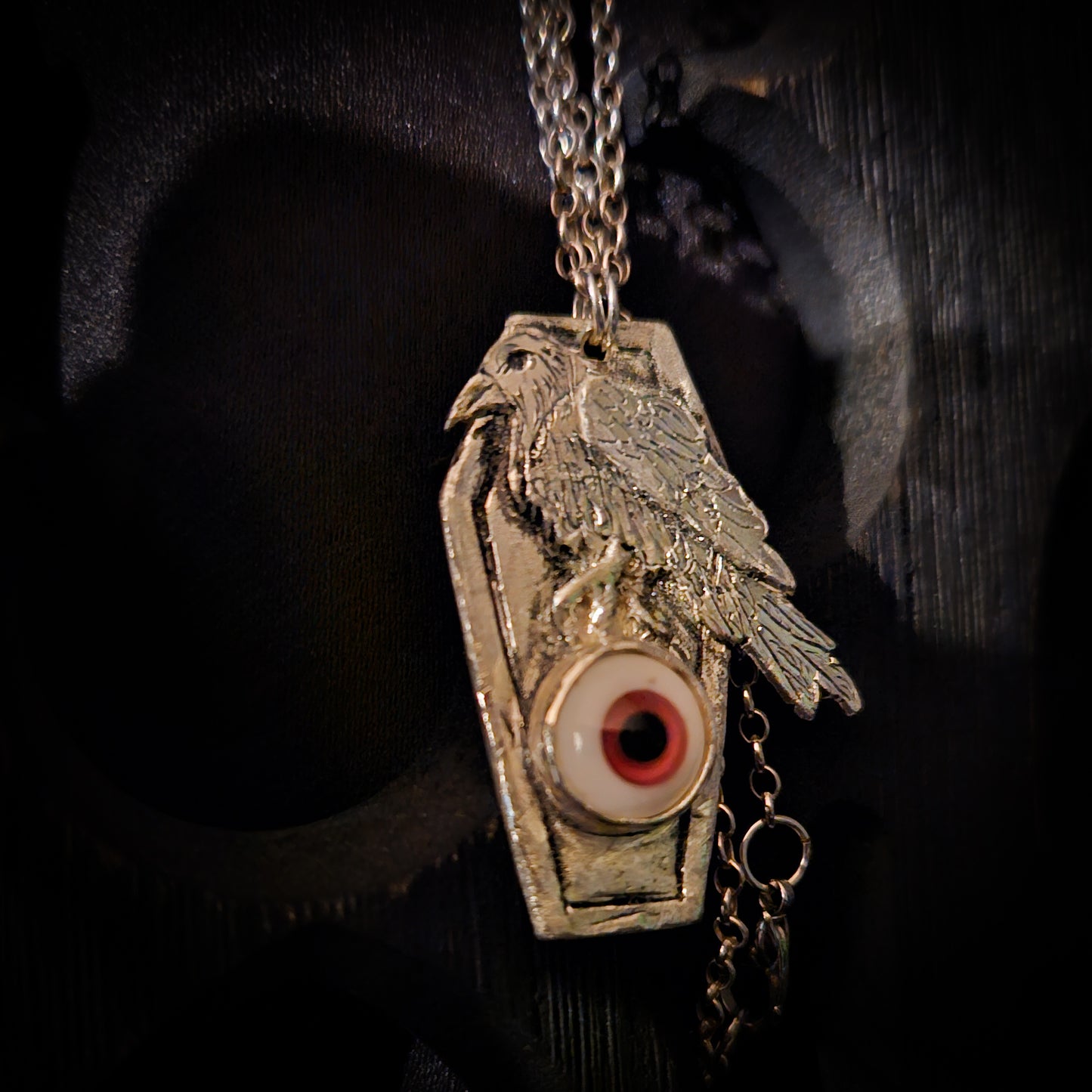 Pendant with a bird design and eye emblem on a dark background
