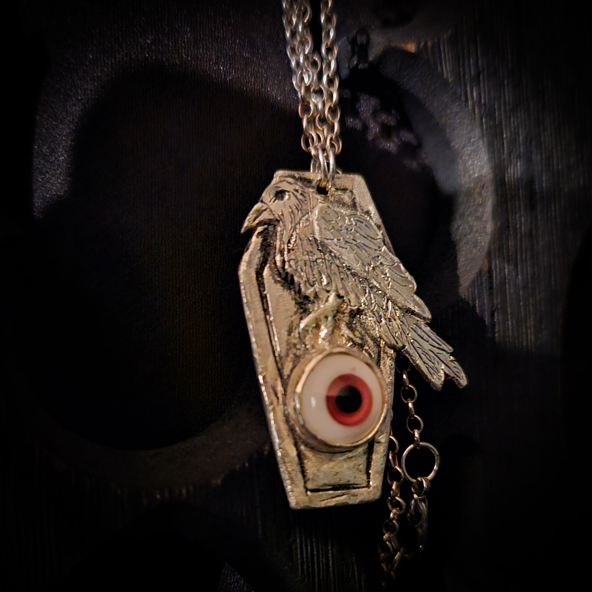 Pendant with a bird design and eye emblem on a dark background