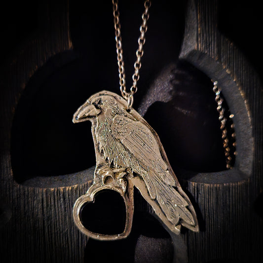 Sterling silver bird pendant with black heart stone on a chain against a dark wooden background