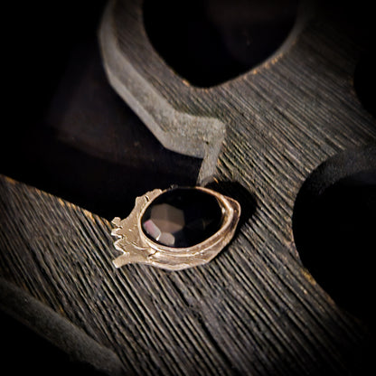 Silver ring with a black stone set on a heart shaped base displayed a wooden surface