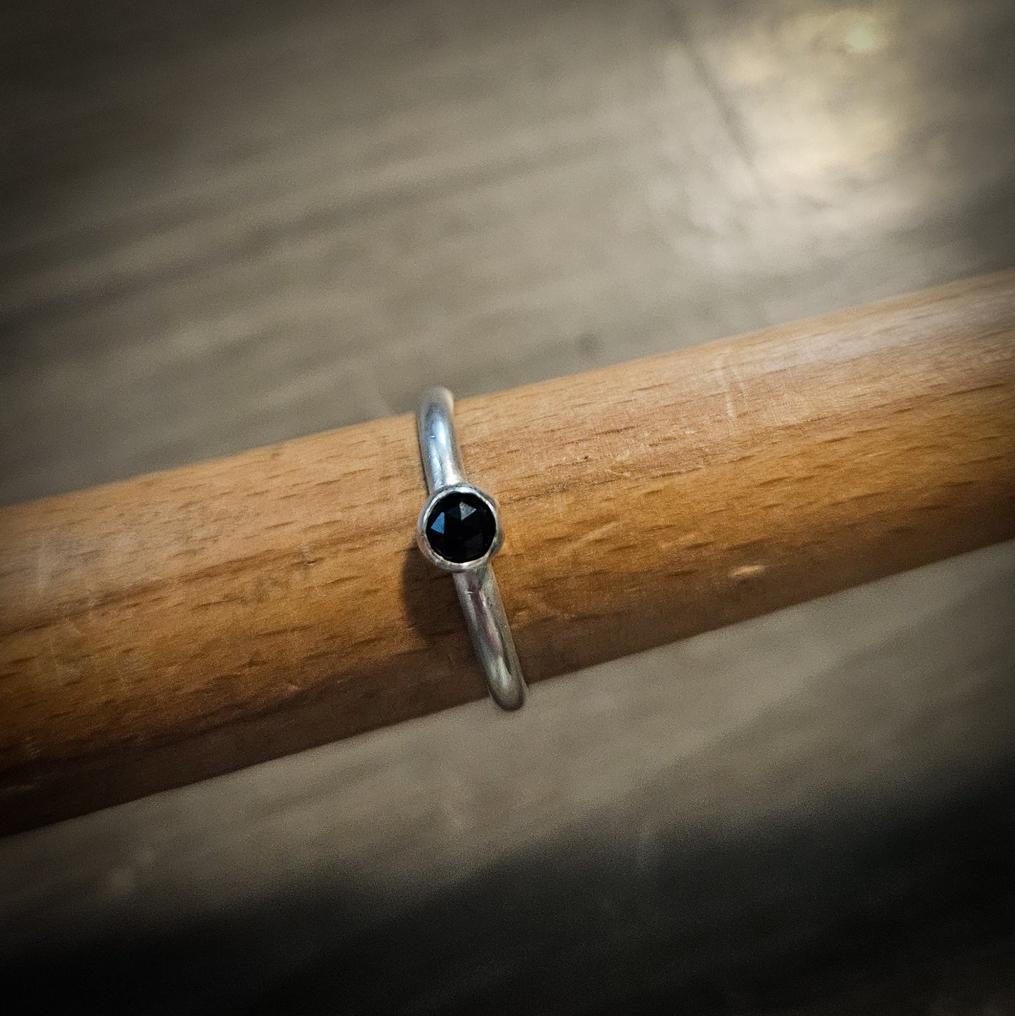 Silver ring with a black gemstone on a wooden stick