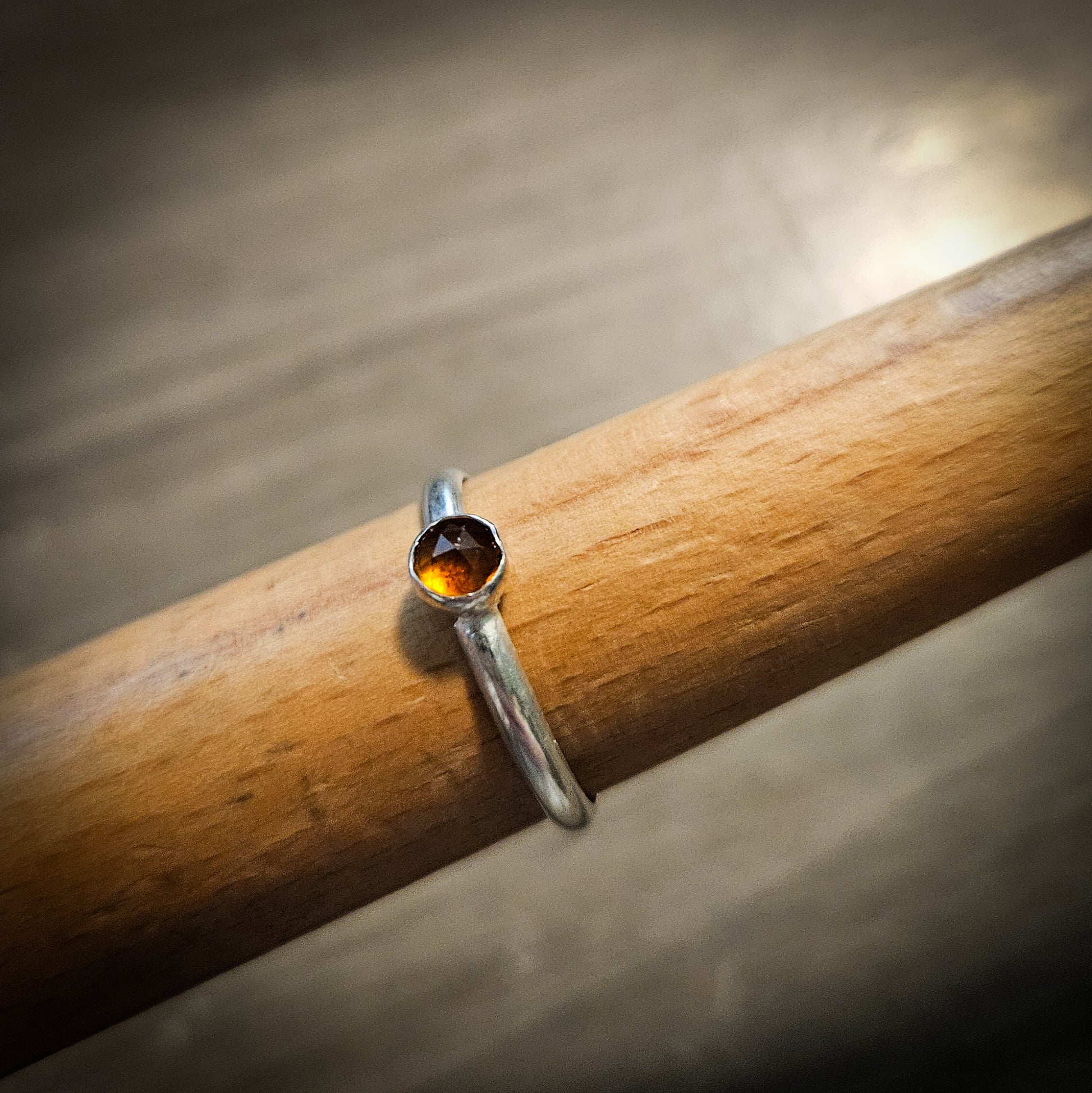 Silver ring with an orange colored gemstone on a wooden stick