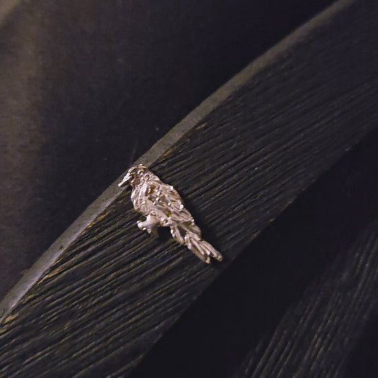 Sterling silver bird-shaped decorative item on a dark wooden surface