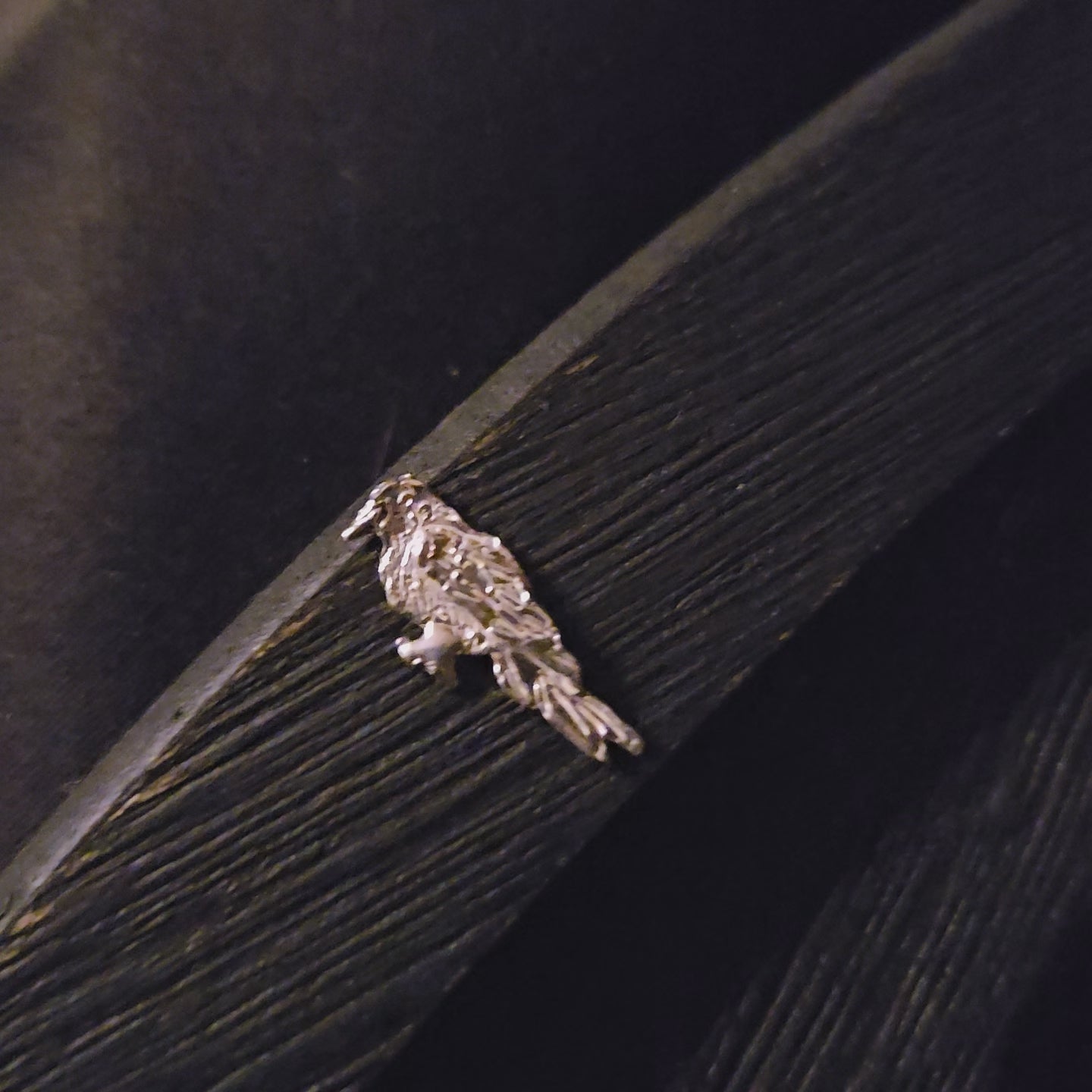 Sterling silver bird-shaped decorative item on a dark wooden surface