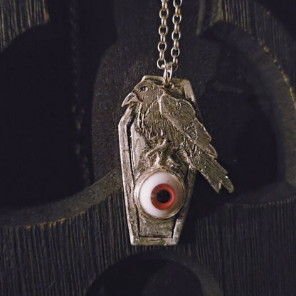 Silver pendant with an eye design on a dark background