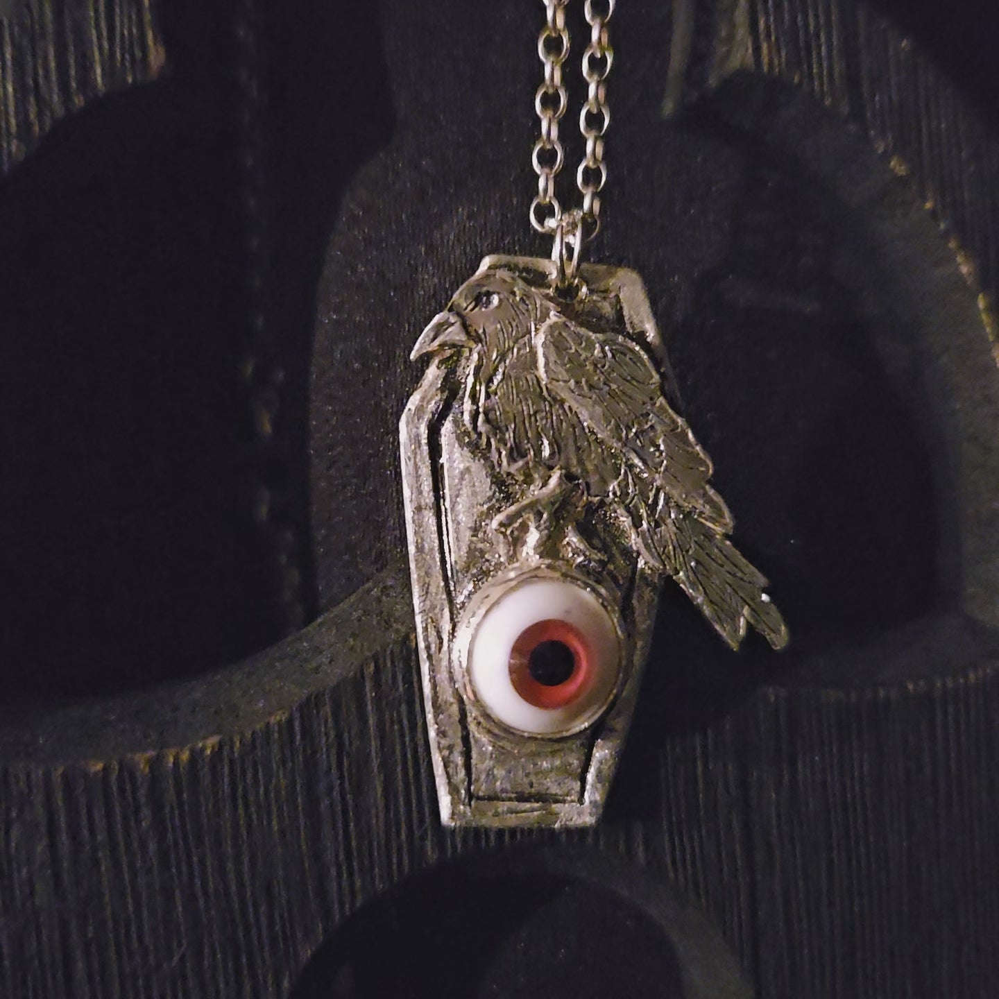 Silver pendant with an eye design on a dark background