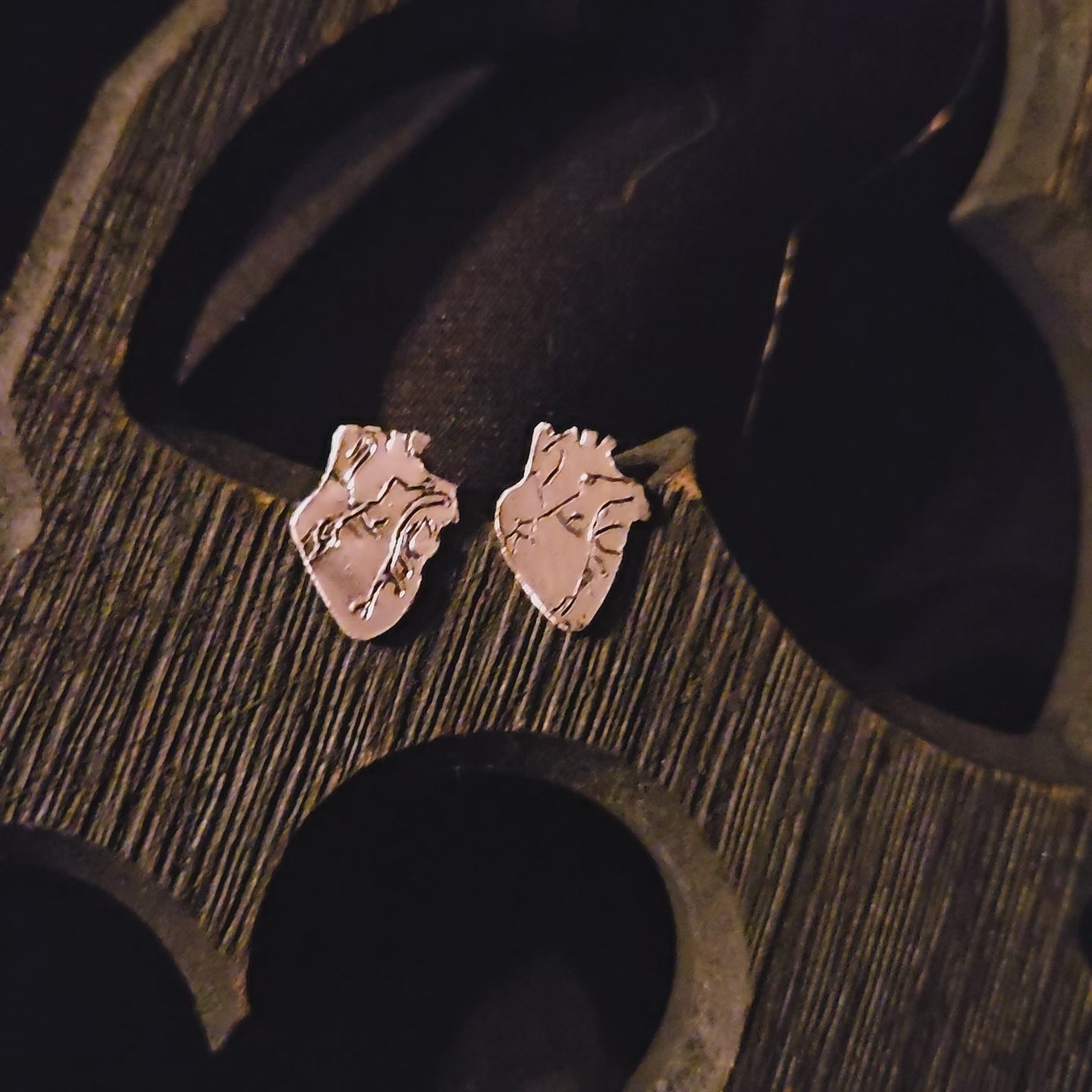 Sterling silver anatomical heart earrings on a dark wooden surface