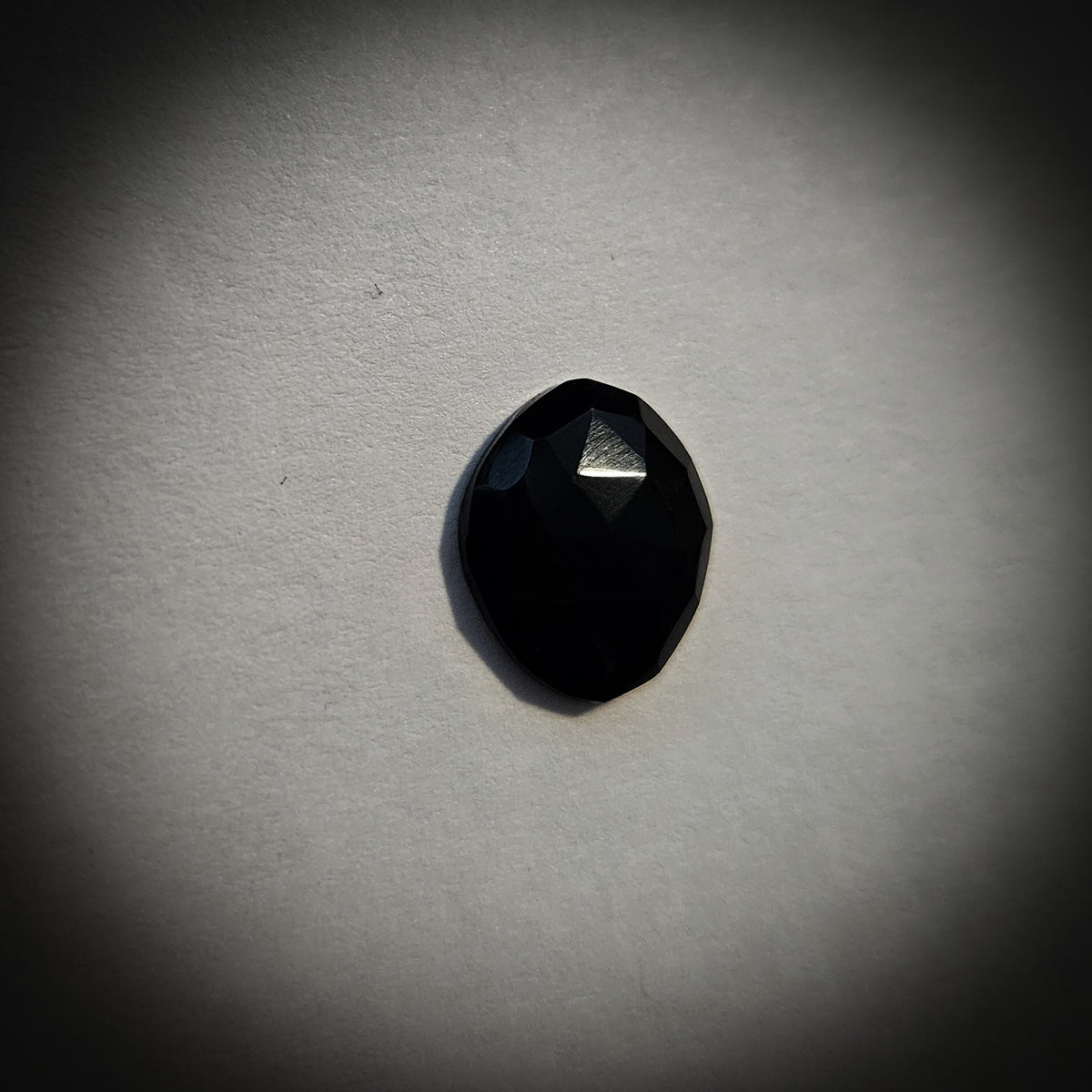 Stone option four, faceted black gemstone on a light gray background 
