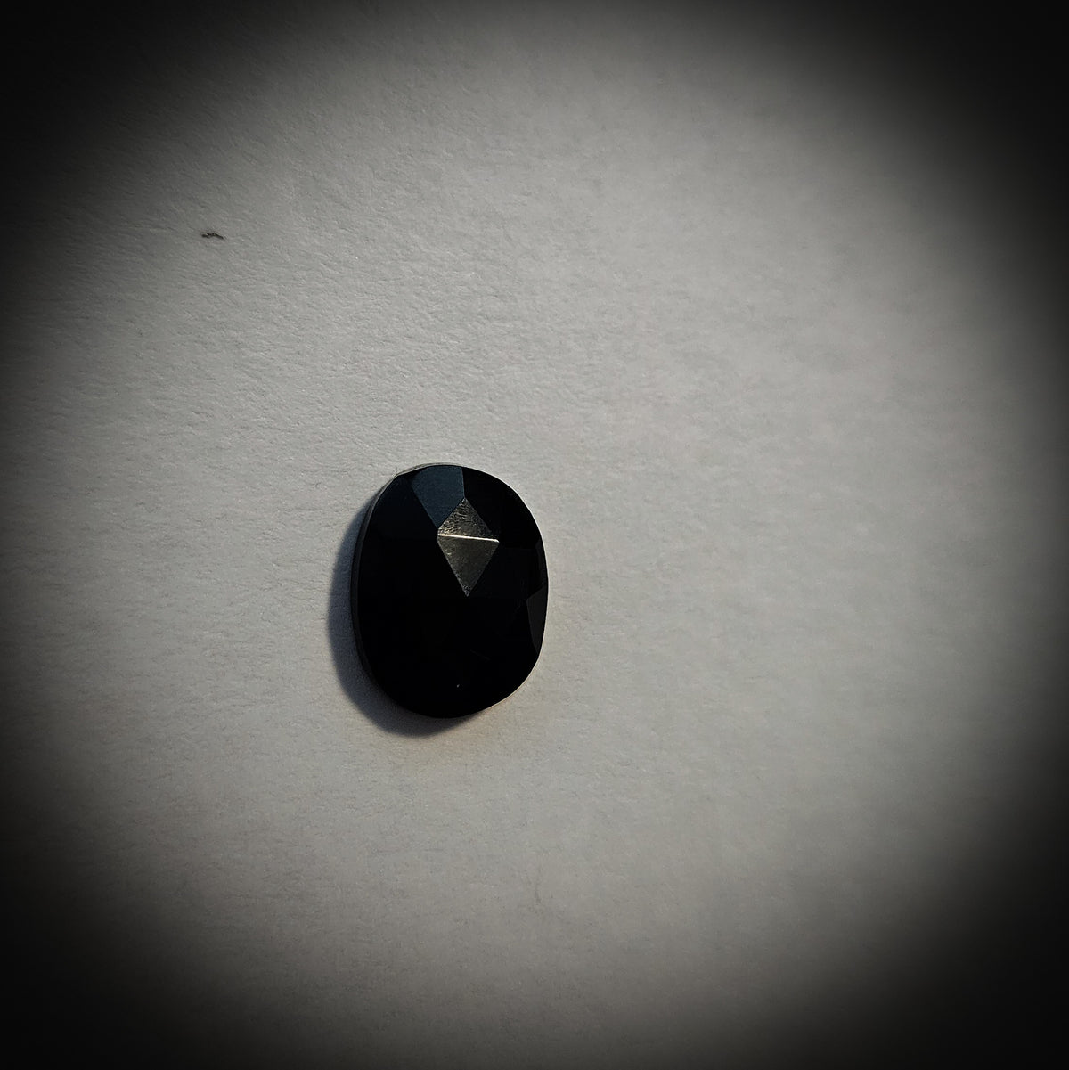 Stone option five, faceted black gemstone on a light gray background 