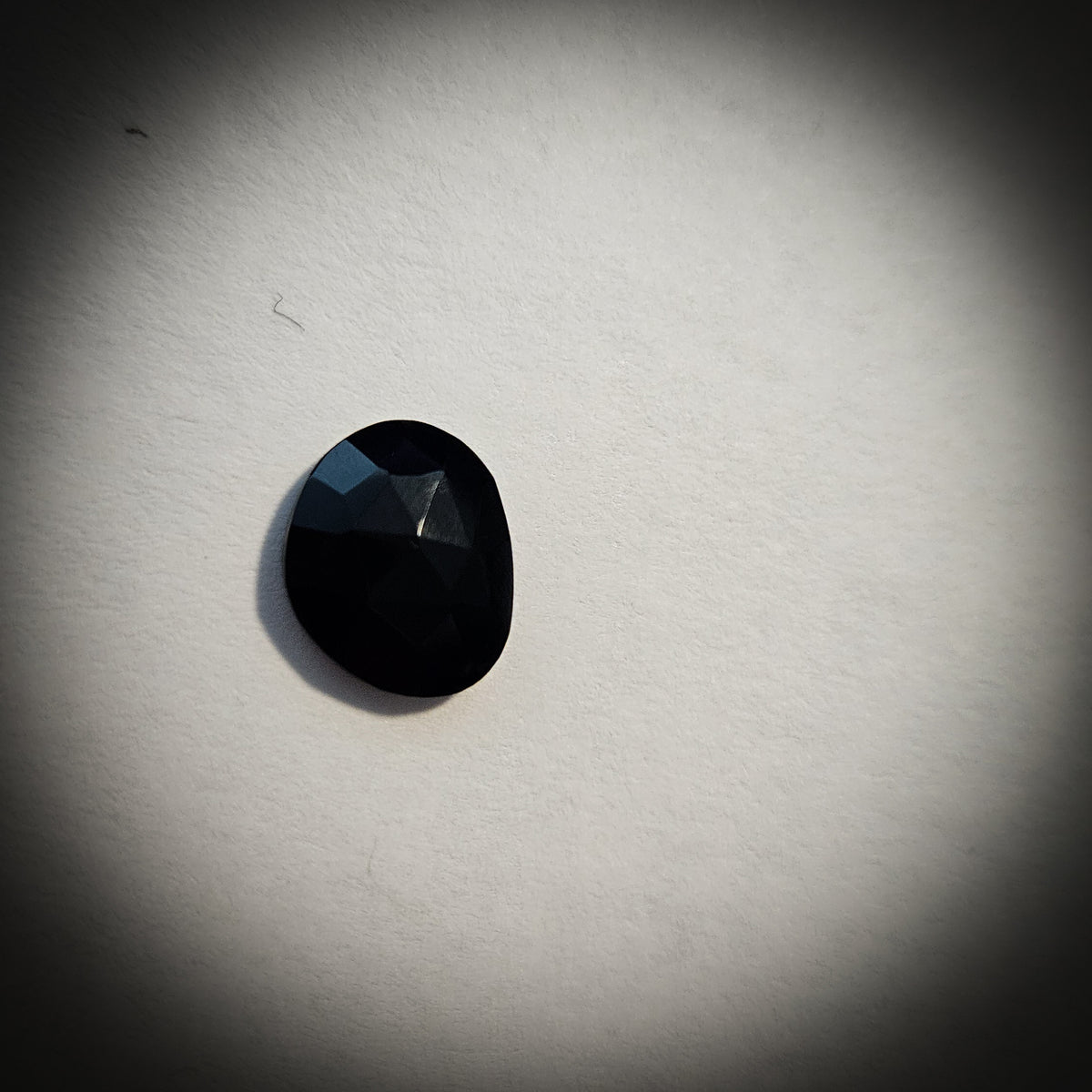 Stone option six, faceted black gemstone on a light gray background 